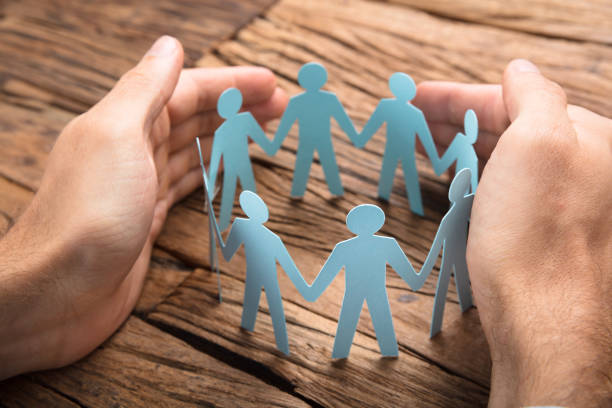 Cropped image of businessman's hands covering paper team on wooden table